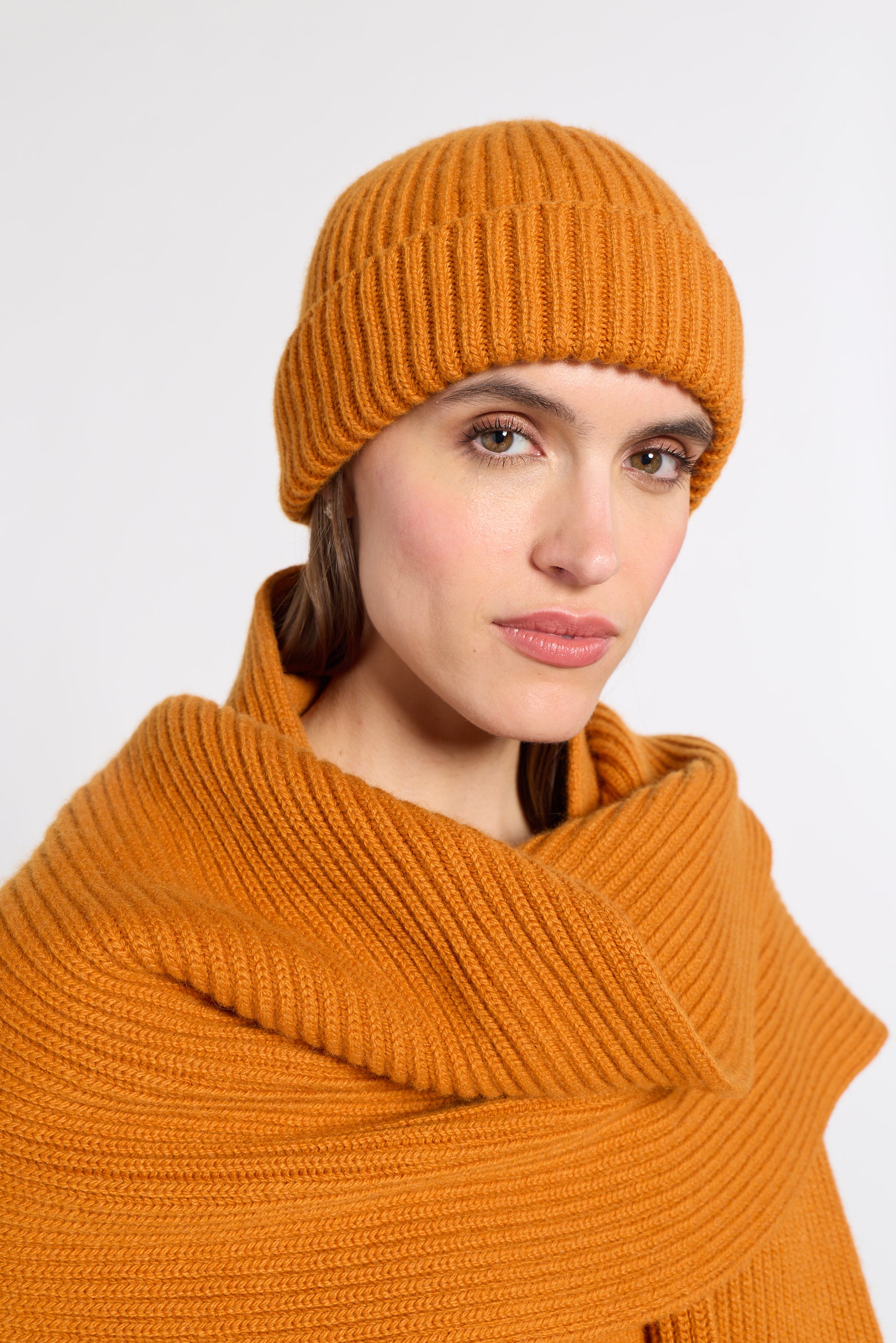 Woman modeling an orange 100% cashmere hat in a studio