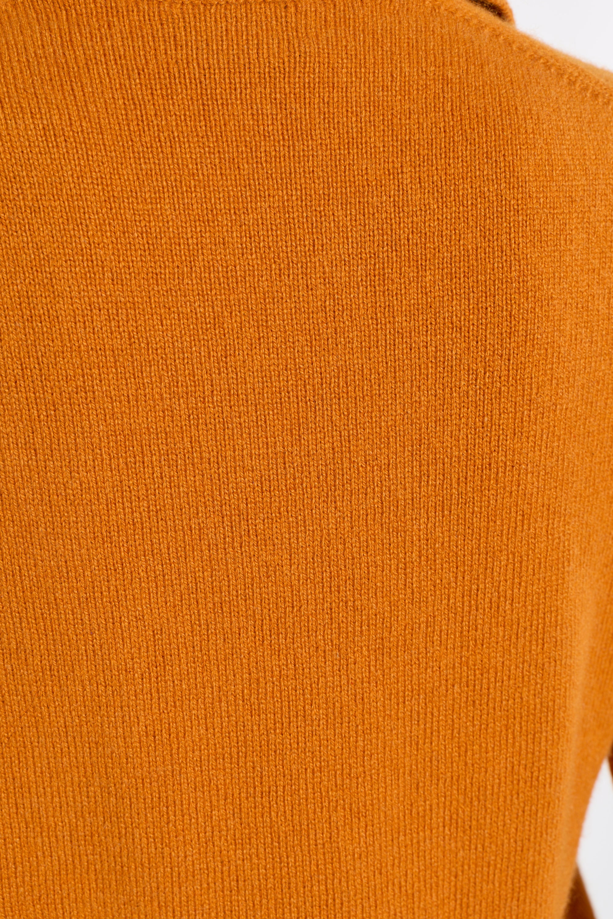 Close-up of a ribbed knit fabric in a warm burnt orange color.