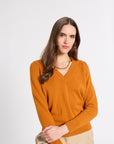 Woman modeling an orange v-neck cashmere sweater