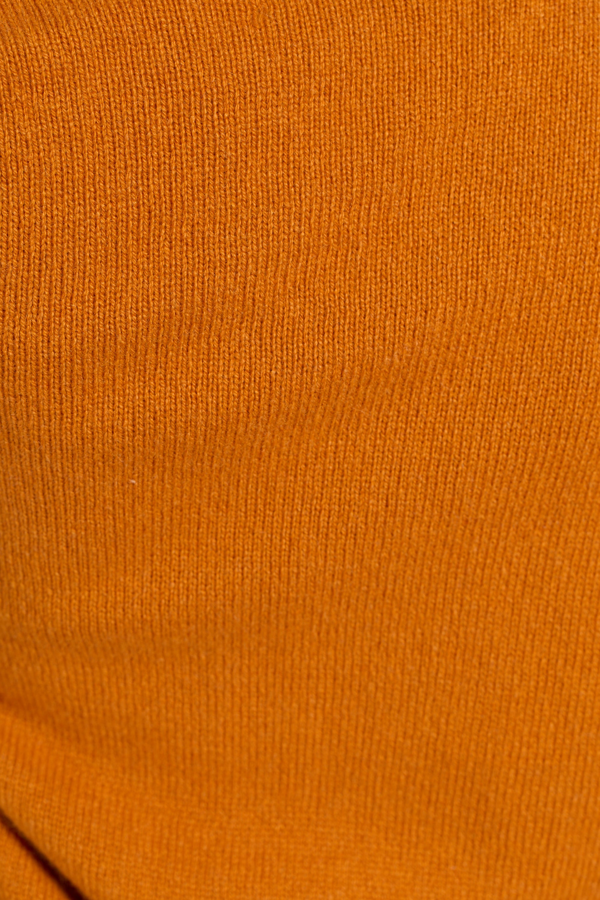 A close-up of a textured knit fabric in a warm orange-brown color.
