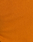 A close-up of a textured knit fabric in a warm orange-brown color.