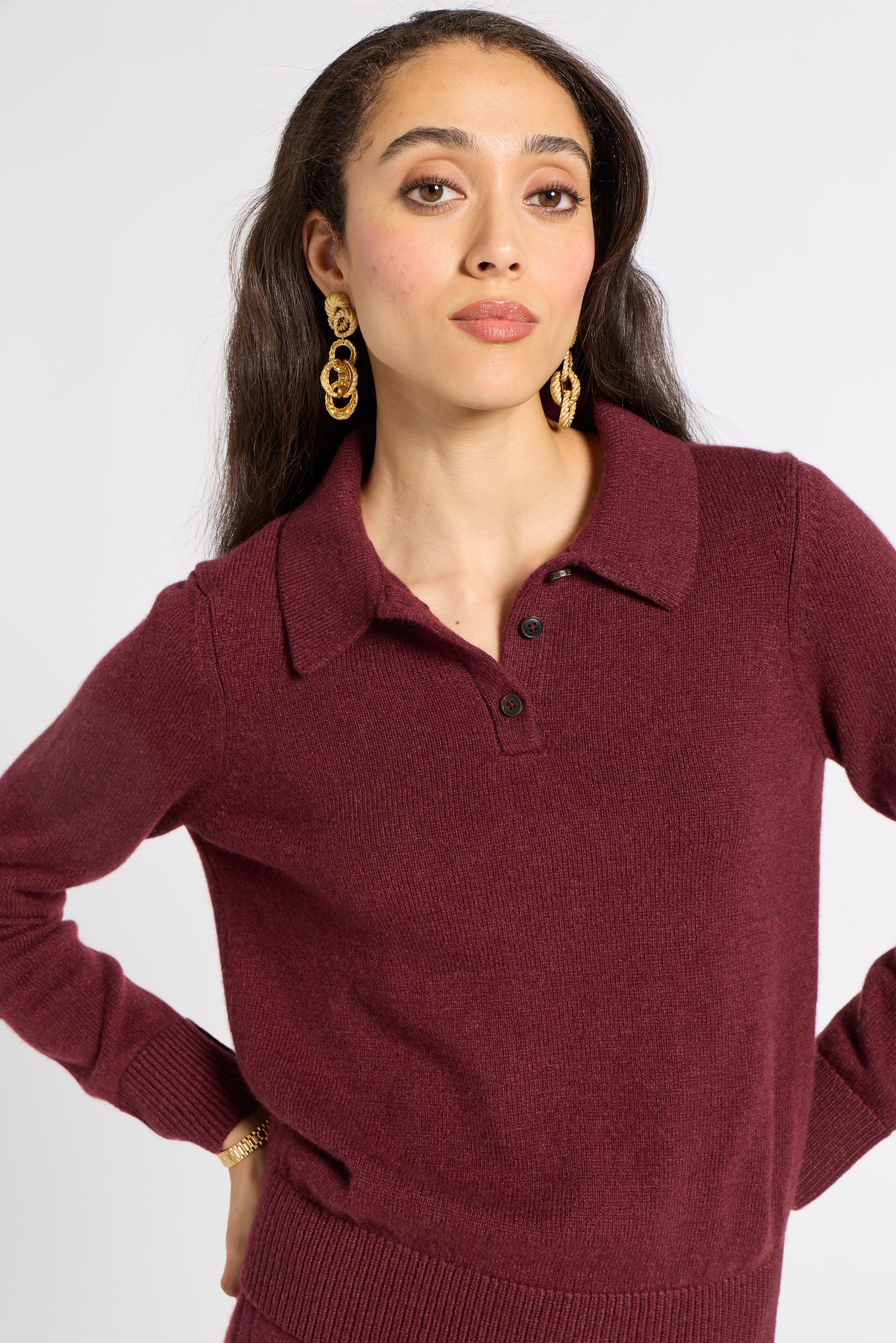 Woman modeling a burgundy polo sweater on a white background