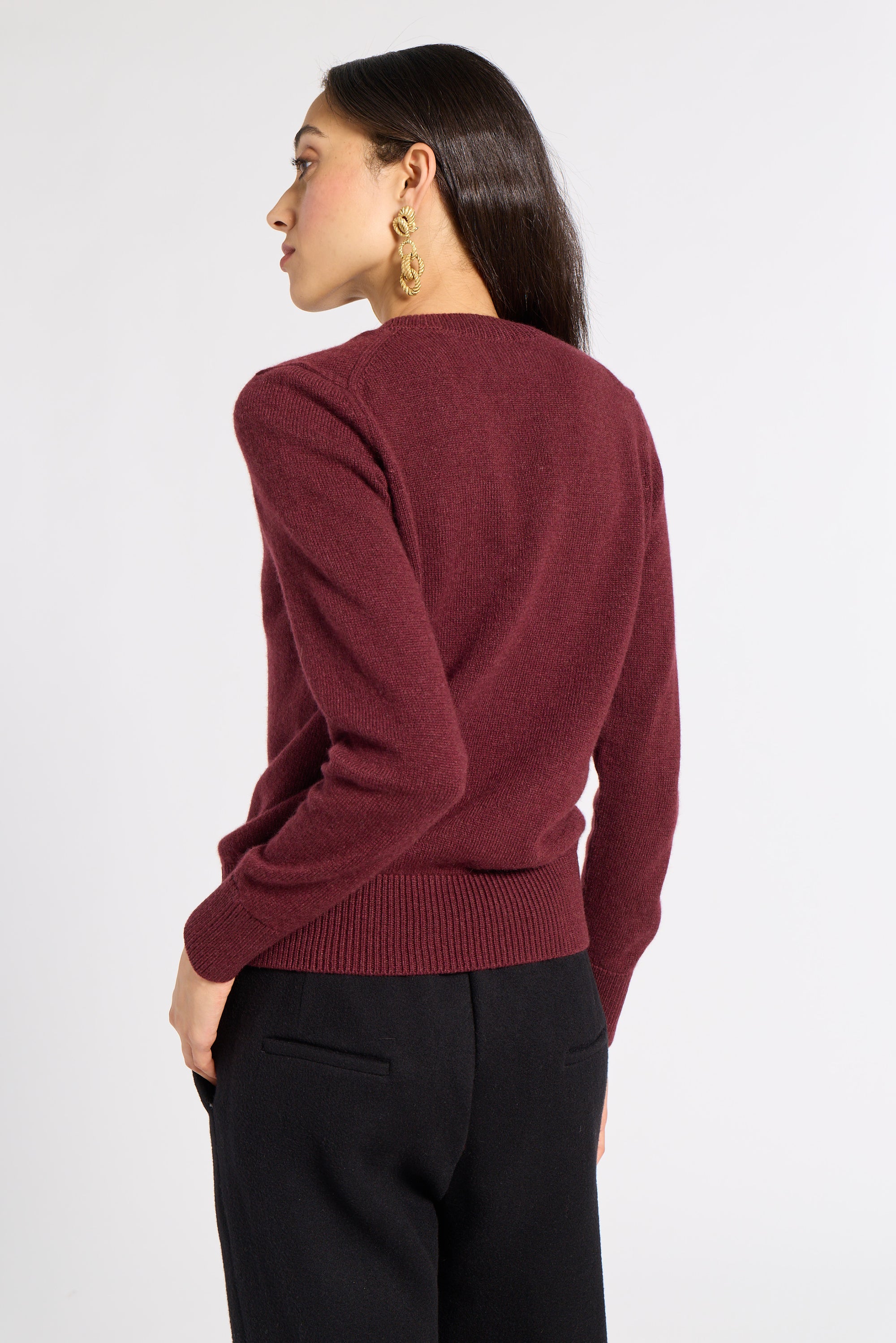Woman modeling a burgundy sweater and black slacks in a studio