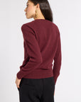 Woman modeling a burgundy sweater and black slacks in a studio