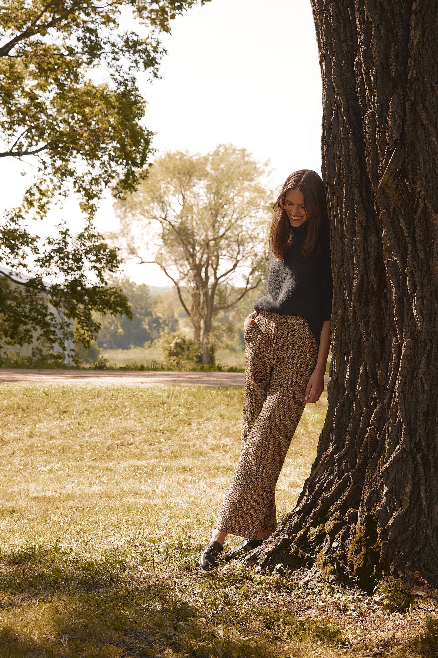 Model wearing a Green Classic Cashmere Crew paired with printed wide-leg pants, standing next to a large tree in a serene outdoor setting