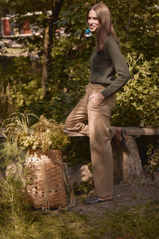 Model wearing a Green Classic Cashmere Crew paired with printed wide-leg pants, standing next to a large tree in a serene outdoor setting.