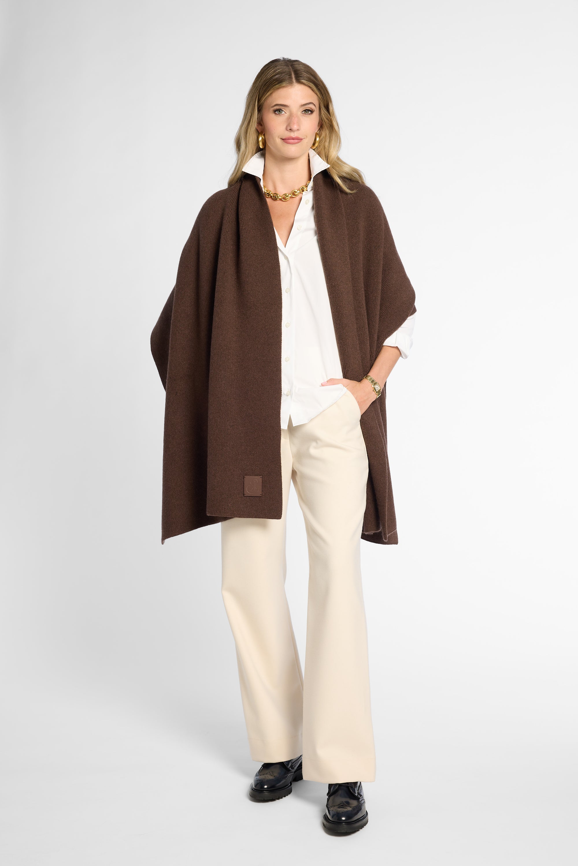 Front View: Woman wearing a chocolate brown wrap on top of a white button up shirt and khakis in front of a white background.