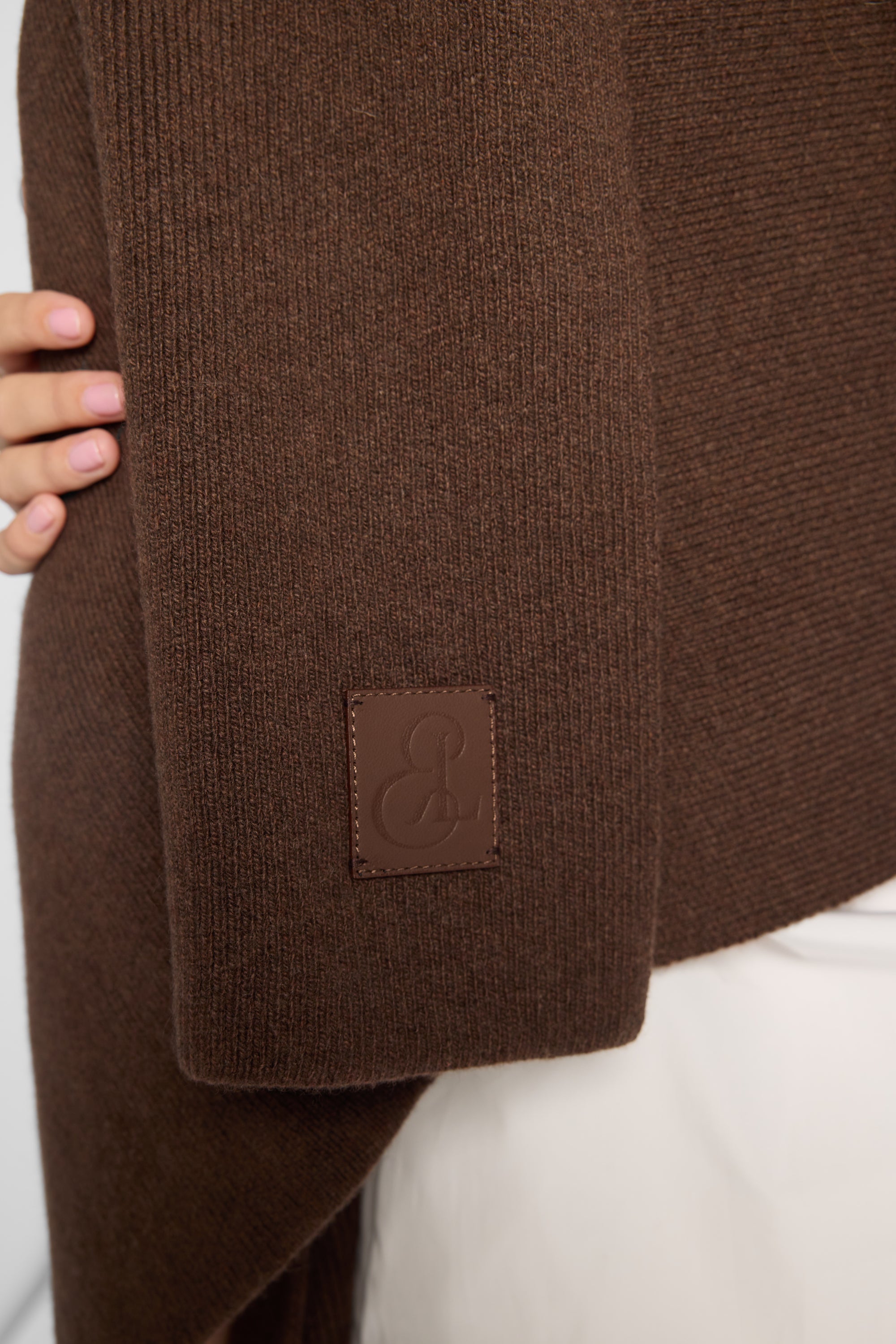 Close View: Woman wearing a chocolate brown wrap with a leather embossed tag.