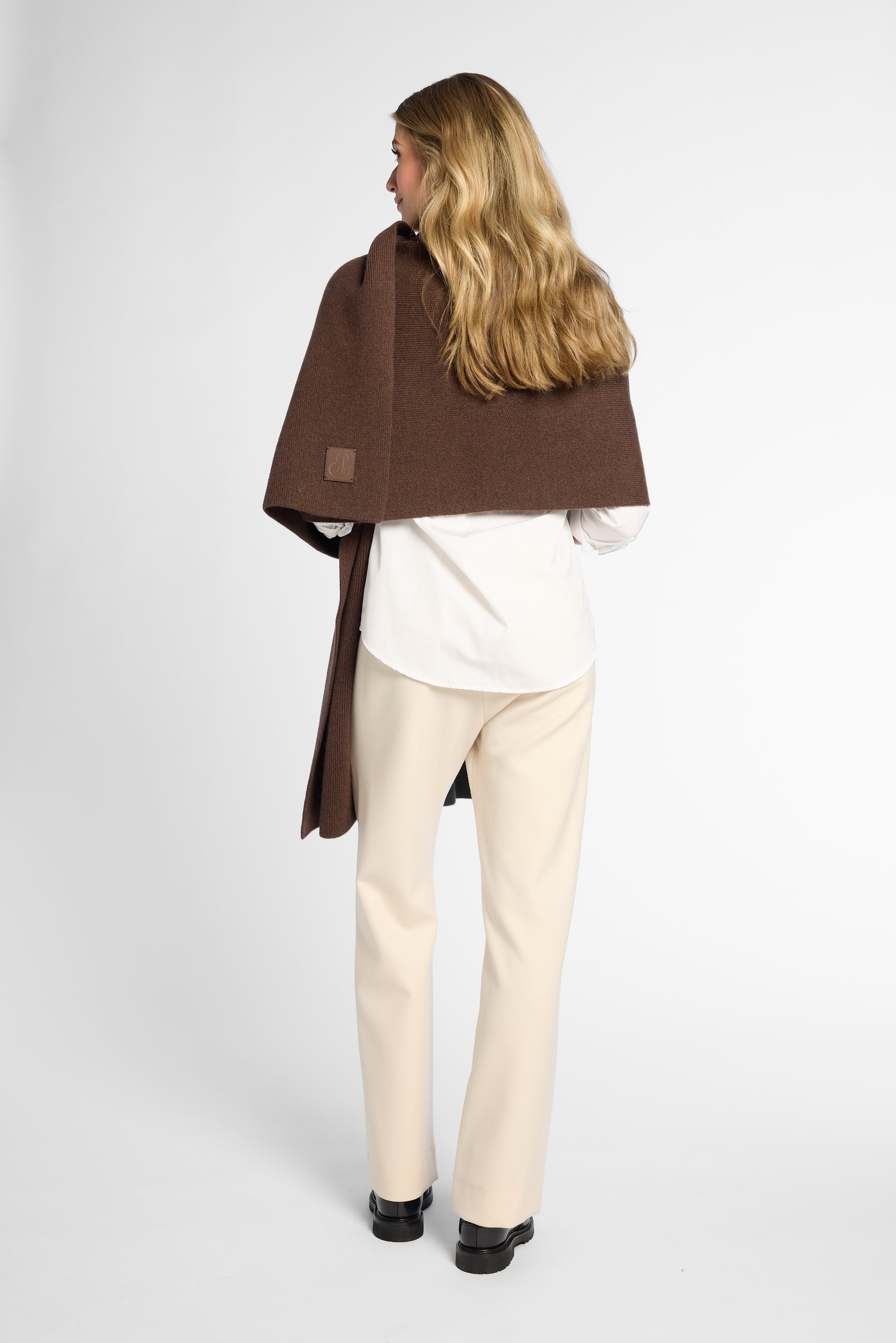 Back View: Woman wearing a chocolate brown wrap on top of a white button up shirt and khakis in front of a white background.