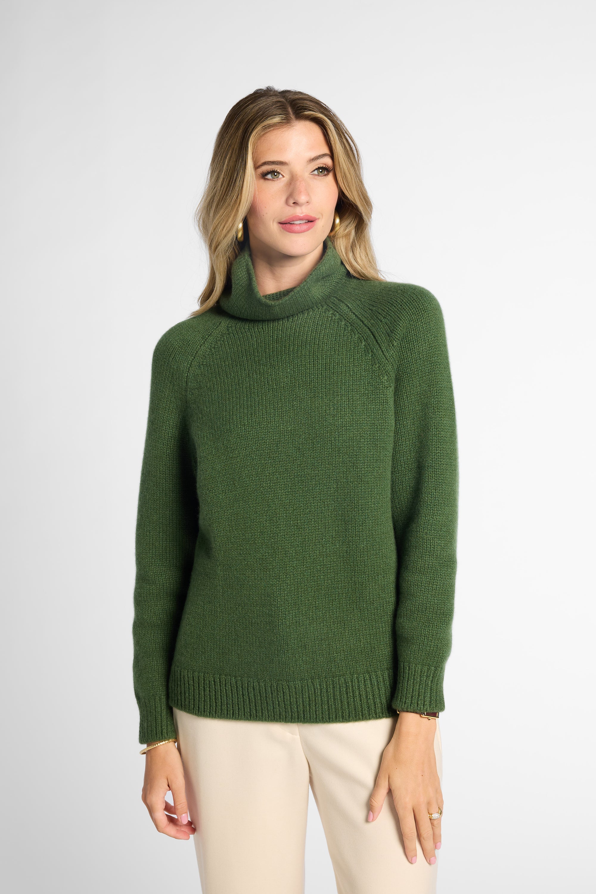 Front view: Woman wearing Forest Green boyfriend turtleneck sweater in front of white background. 