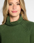 Close view: Woman wearing Forest Green boyfriend turtleneck sweater in front of white background. 