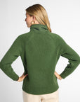 Back view: Woman wearing Forest Green boyfriend turtleneck sweater in front of white background. 