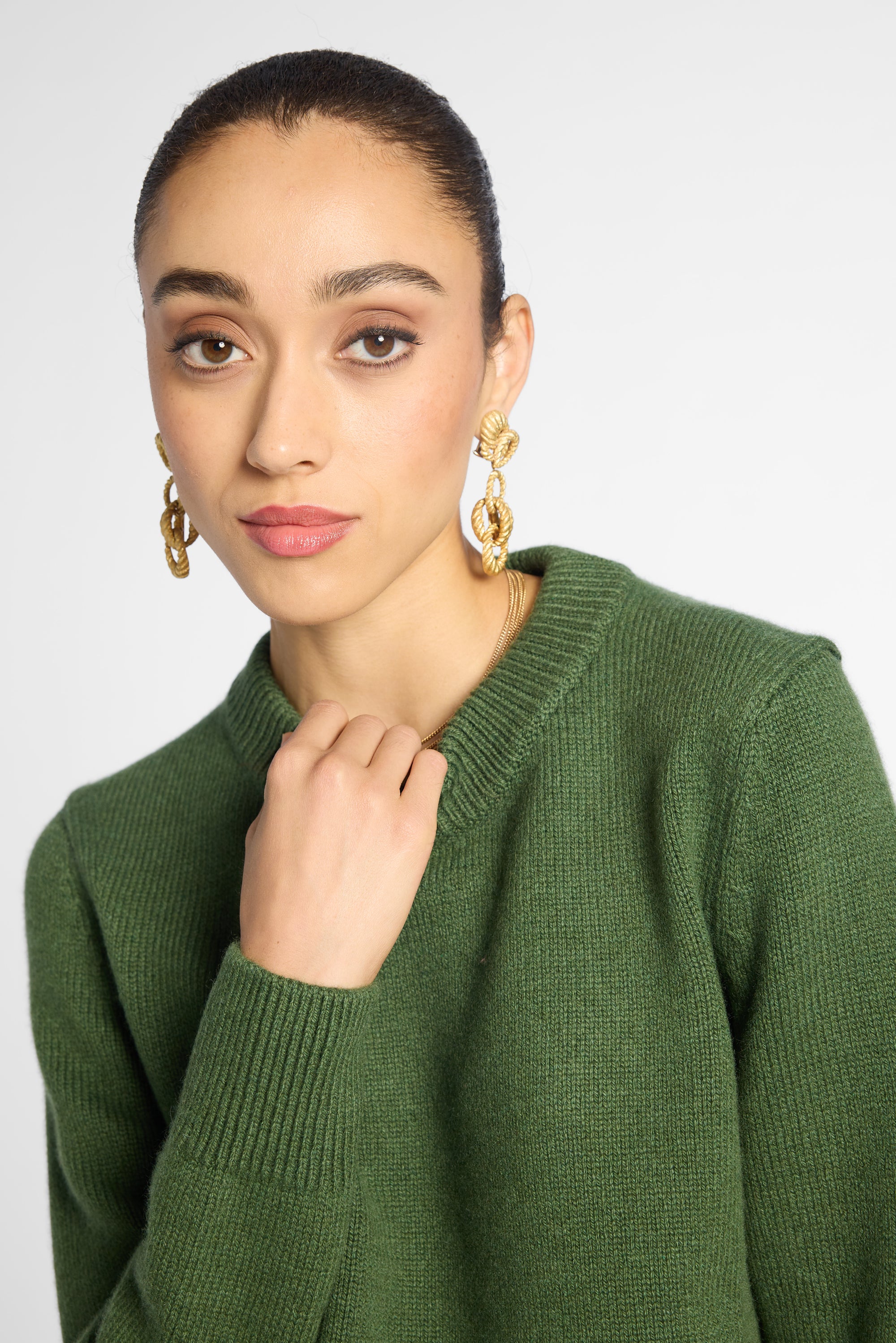 Close view: Woman wearing Forest Green crewneck sweater in front of white background. 