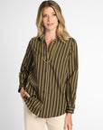 A woman modeling a long-sleeve button-up blouse with vertical olive green and tan stripes, paired with cream pants, against a light gray studio background.
