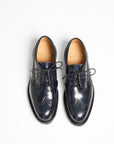 A pair of dark navy blue brogue oxford shoes with black laces, shown from a top-down view on a clean white background. The brand name 'MACKENZIE' is visible on the tan insole of each shoe.