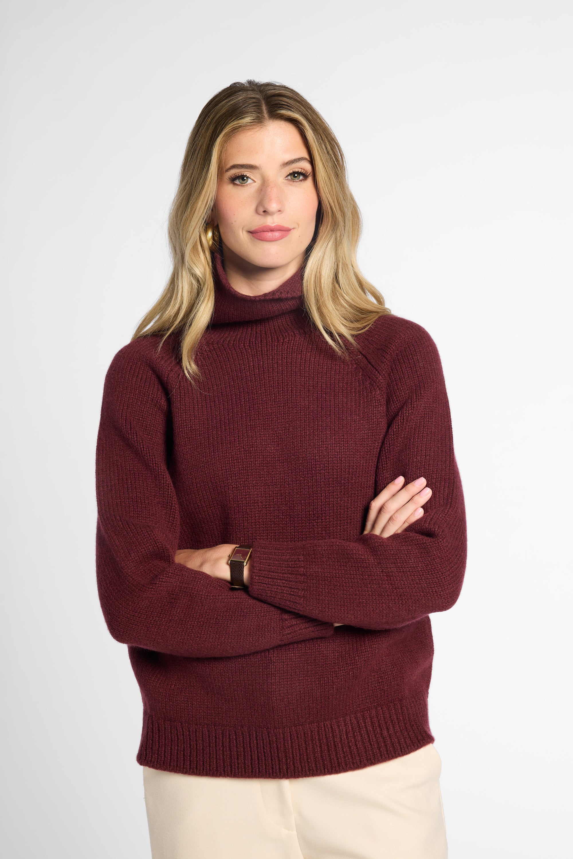 Front view of woman in wine-colored boyfriend turtleneck sweater in front of a white background.