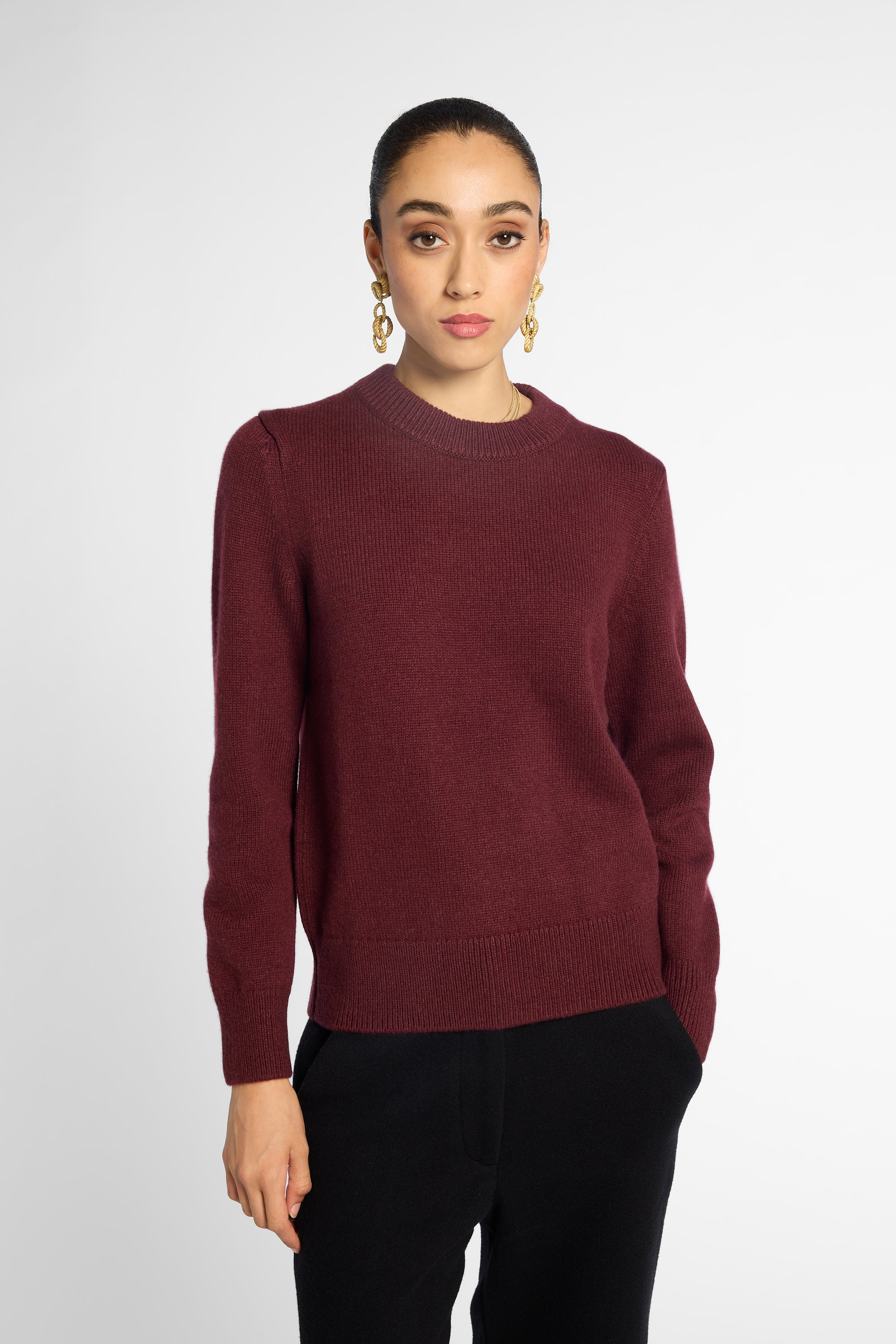 Front view of woman in wine-colored crew neck cardigan in front of a white background.