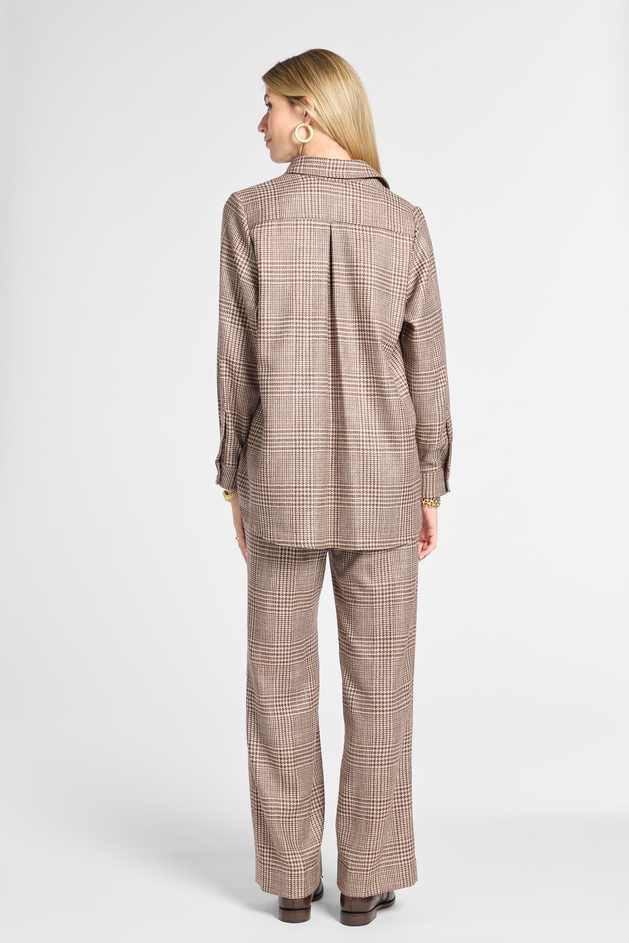 A woman shown from the back wearing a matching brown and beige plaid blazer and wide-leg trousers set, photographed against a light gray studio background.