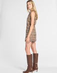 A woman modeling a sleeveless, multicolor tweed mini dress paired with brown knee-high leather boots, photographed against a light gray studio background.