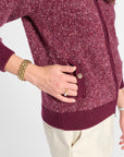Button and pocket detail of a purple bomber jacket and white pants