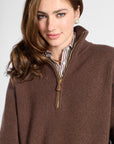 A woman wearing a brown ribbed knit quarter-zip sweater over a striped collared shirt, photographed against a light gray studio background.