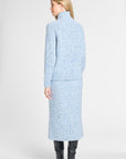 A model shown from the back wearing a light blue knit turtleneck sweater and matching midi skirt set with a subtle speckled texture, paired with black knee-high boots, against a light gray studio background.