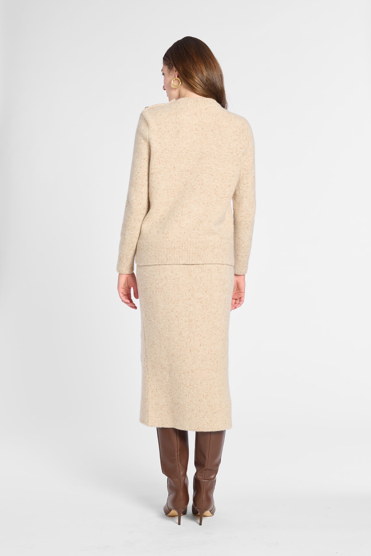 A woman shown from the back wearing a matching beige knit jacket and midi skirt set, paired with brown knee-high boots, against a light gray studio background.