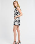 Woman wearing a black and white floral blouse and shorts on a white backdrop