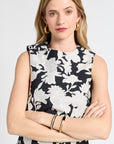 Woman modeling a black and white top with gold jewelry on a white background