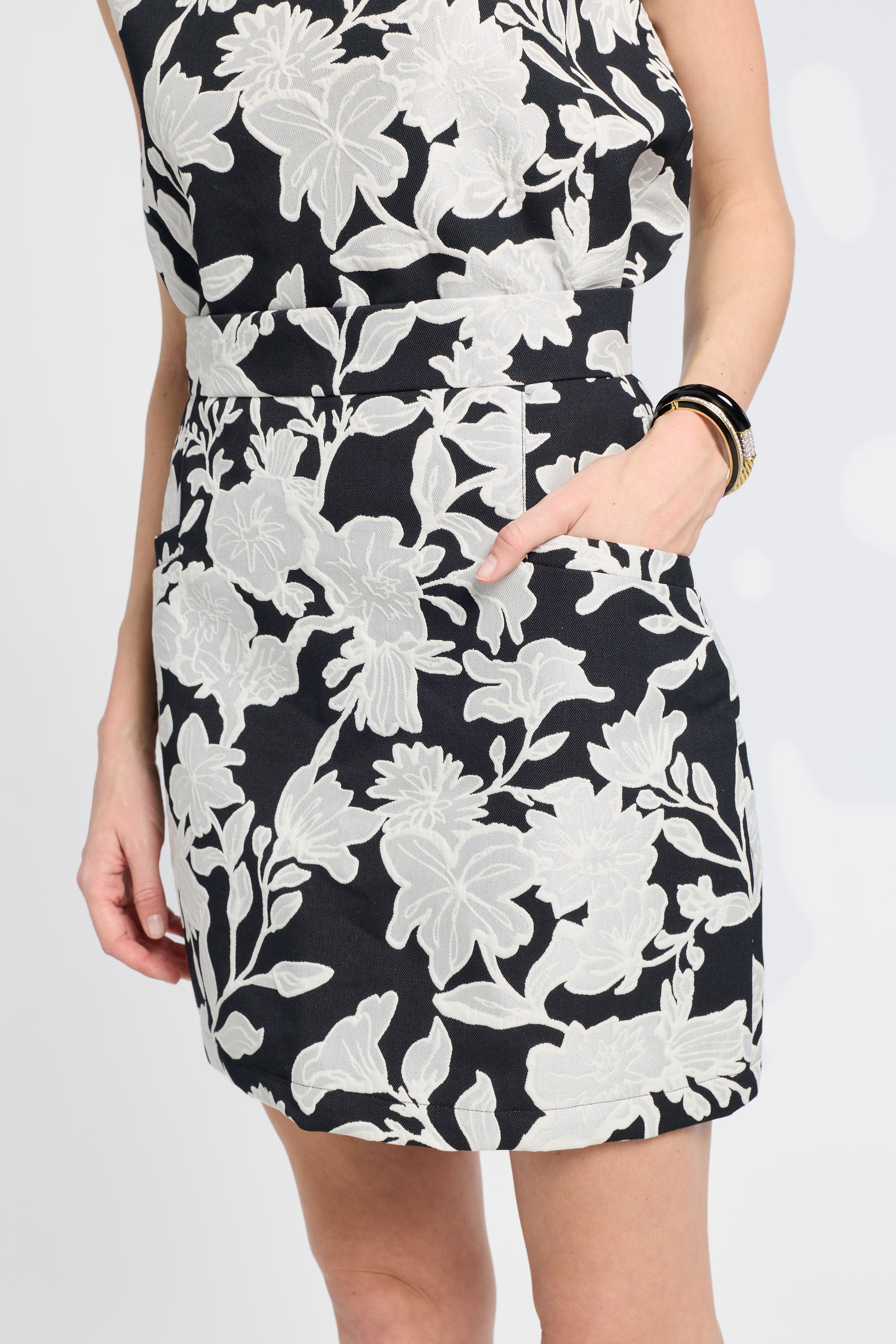 Black skirt with white floral pattern worn by a person on a white background