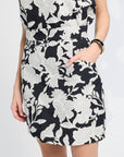 Black skirt with white floral pattern worn by a person on a white background