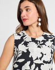 Woman wearing a black and white floral dress with white earrings against a white background