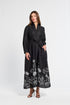 Woman wearing a black maxi dress with floral patterns on a white background