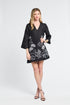 Woman wearing a black dress with floral patterns on a white background