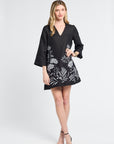 Woman wearing a black dress with floral patterns on a white background
