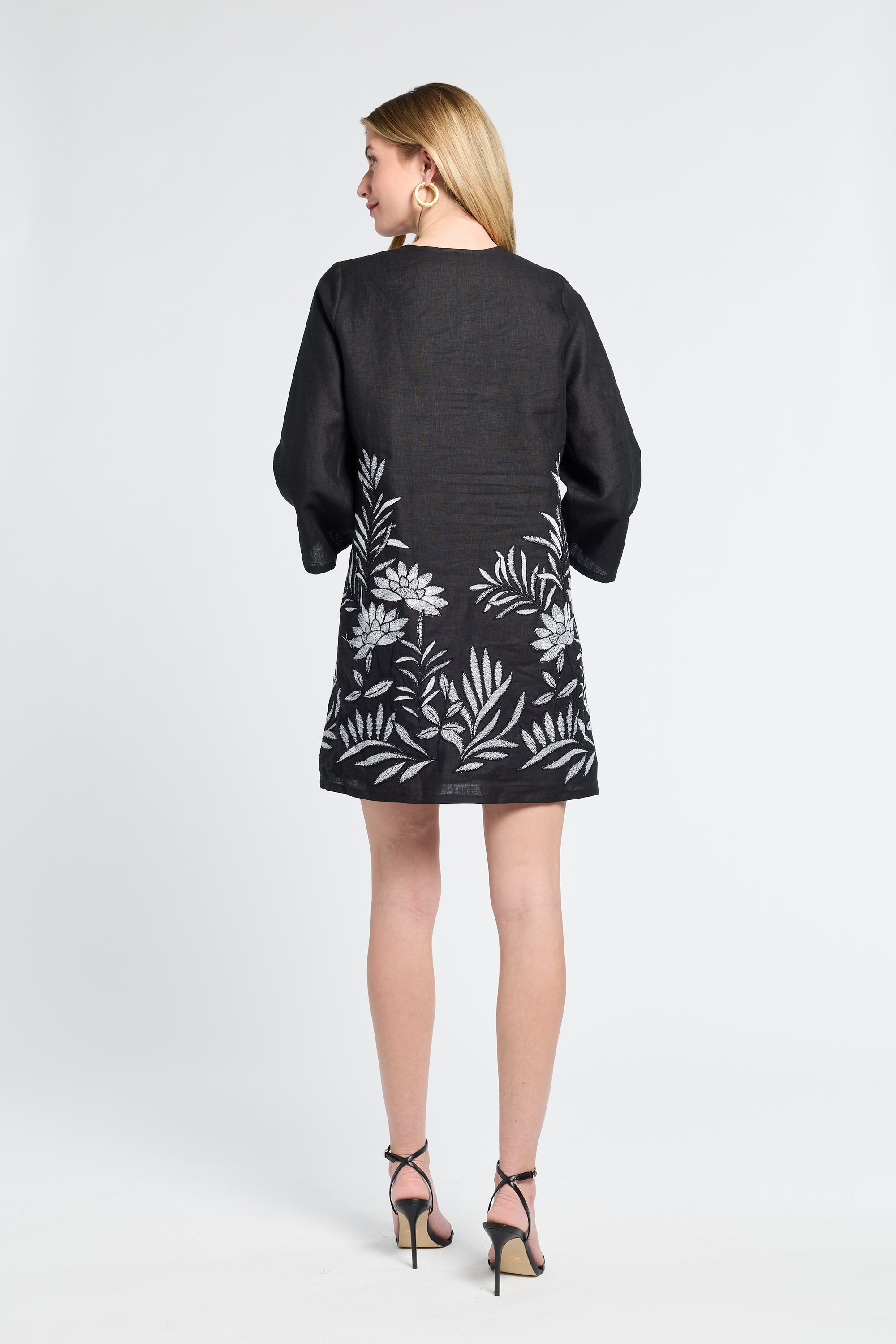 Woman wearing a black dress with floral patterns on a white background
