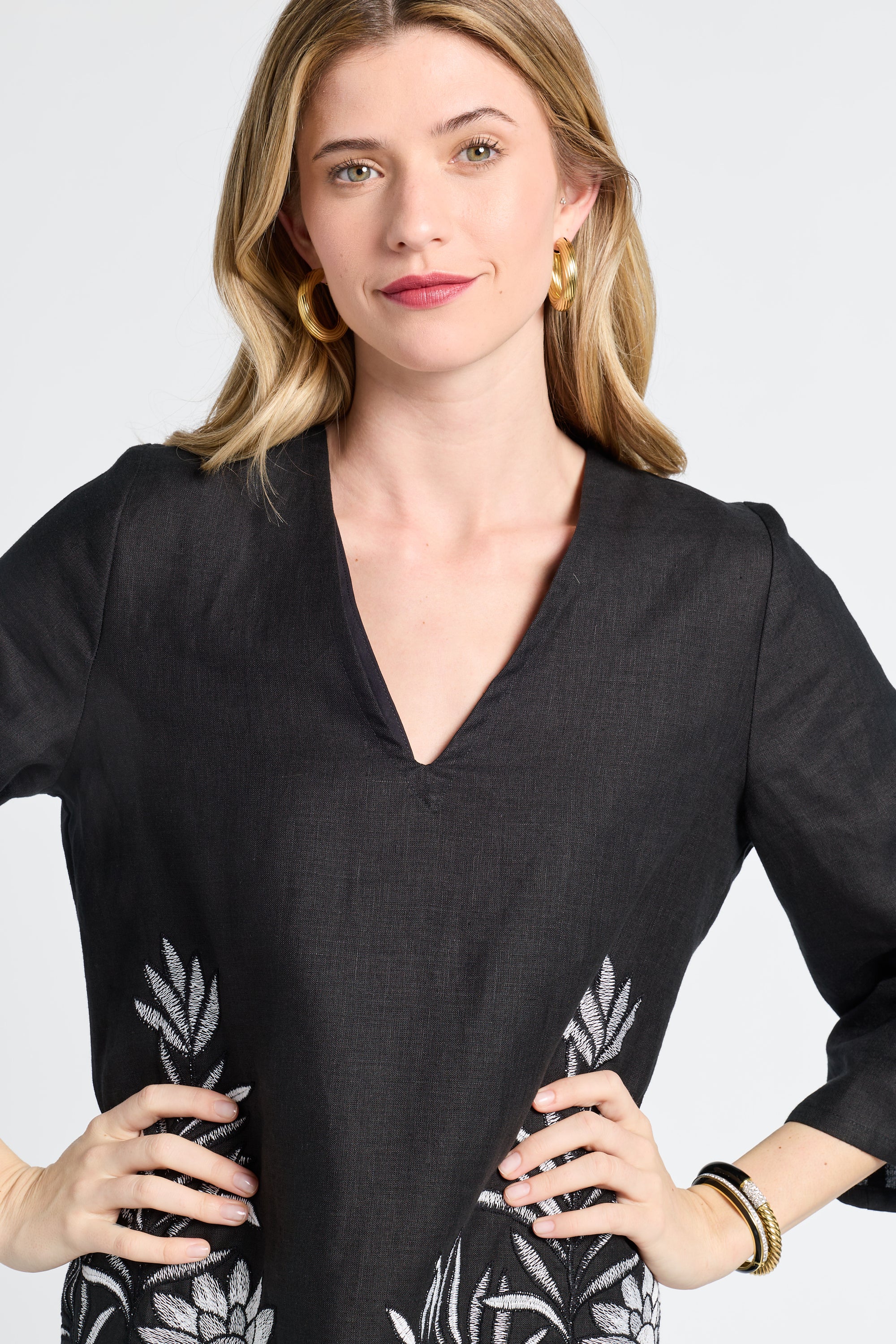 Woman modeling a black dress with floral patterns on a plain background