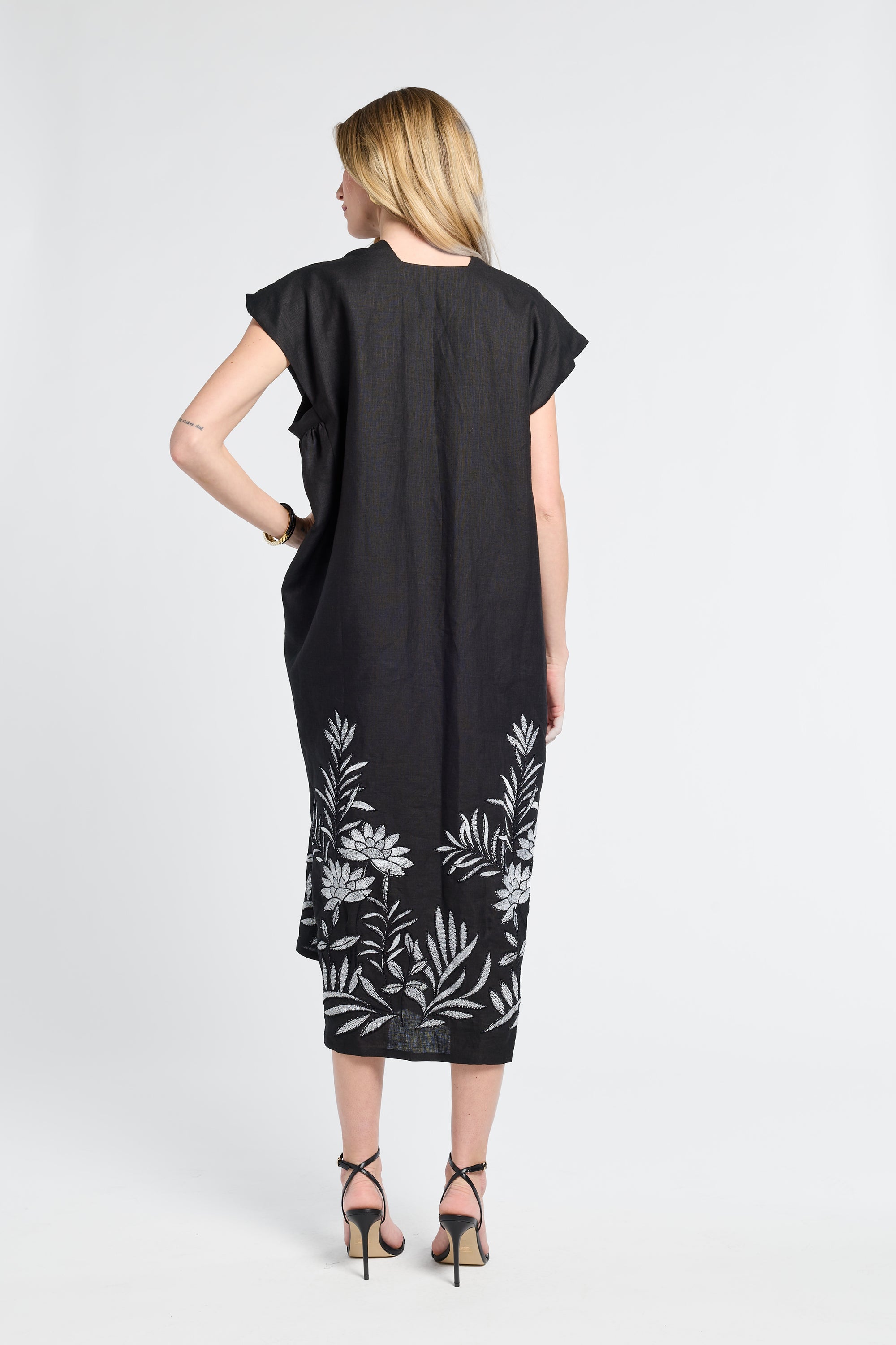 woman wearing a black caftan with black heels on a white backdrop