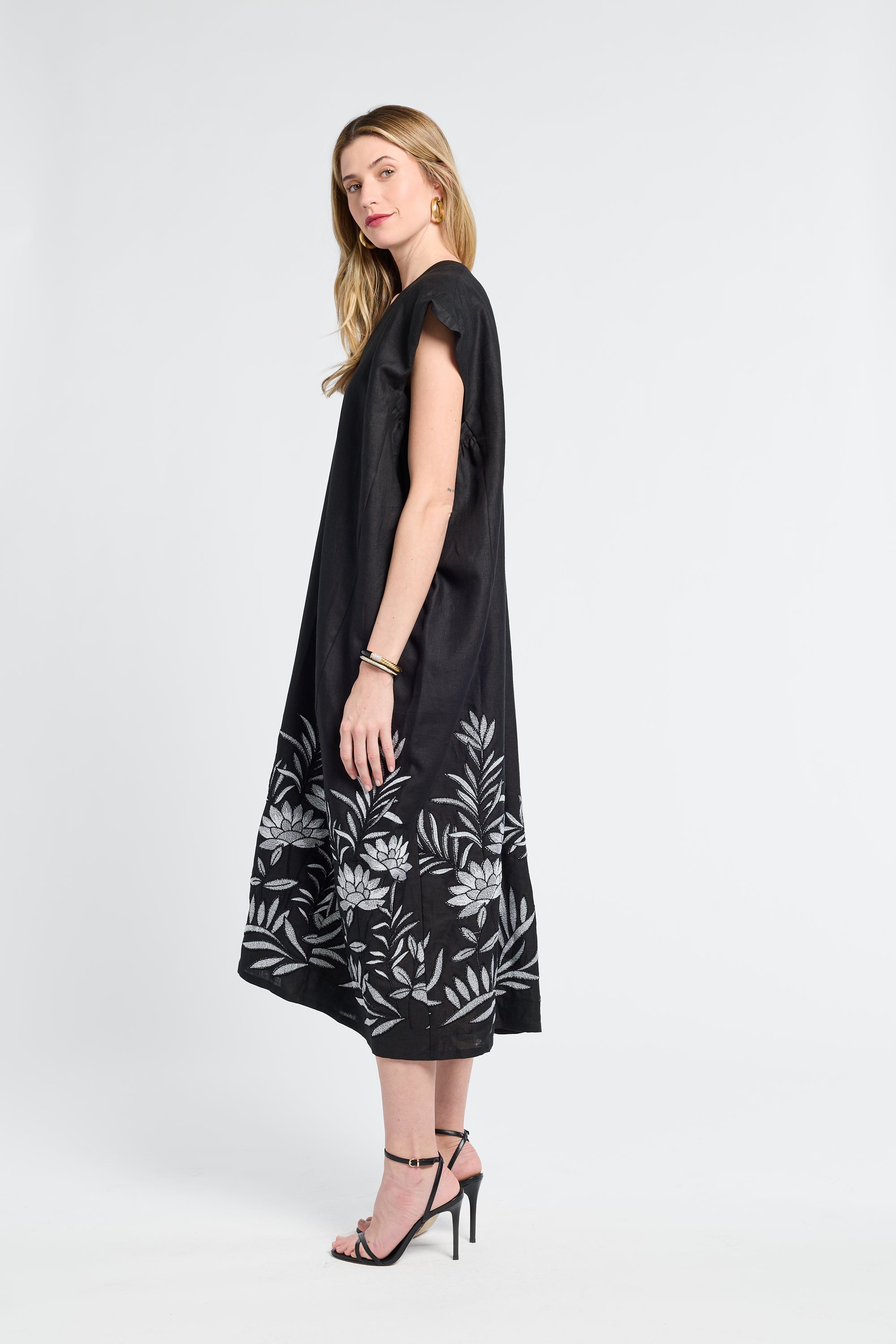 Woman wearing a black dress with floral patterns on a white background
