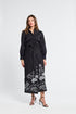 Woman wearing a black pareo with white floral patterns on a white background