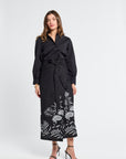 Woman wearing a black pareo with white floral patterns on a white background