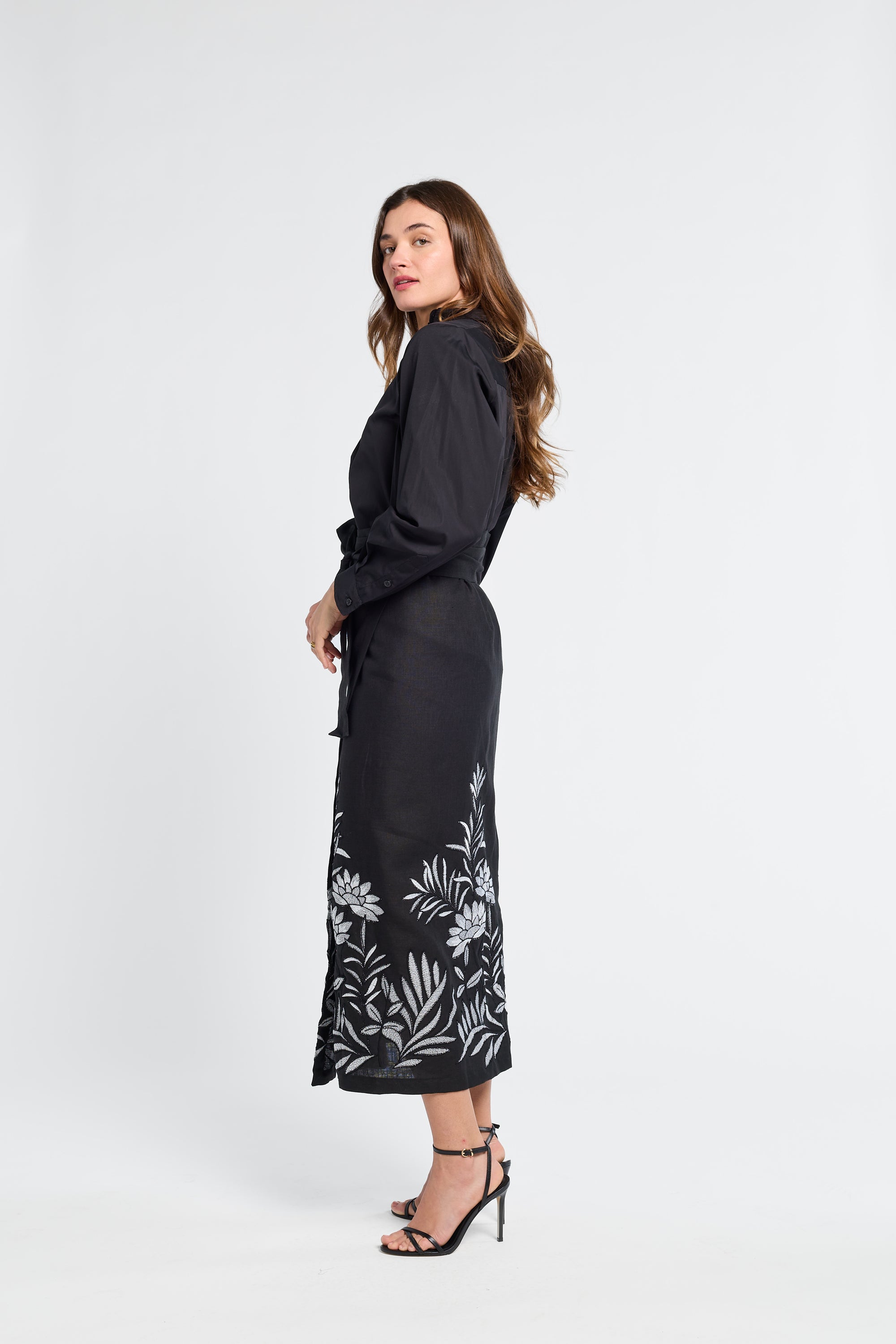 Woman wearing a black dress with floral patterns on a white background