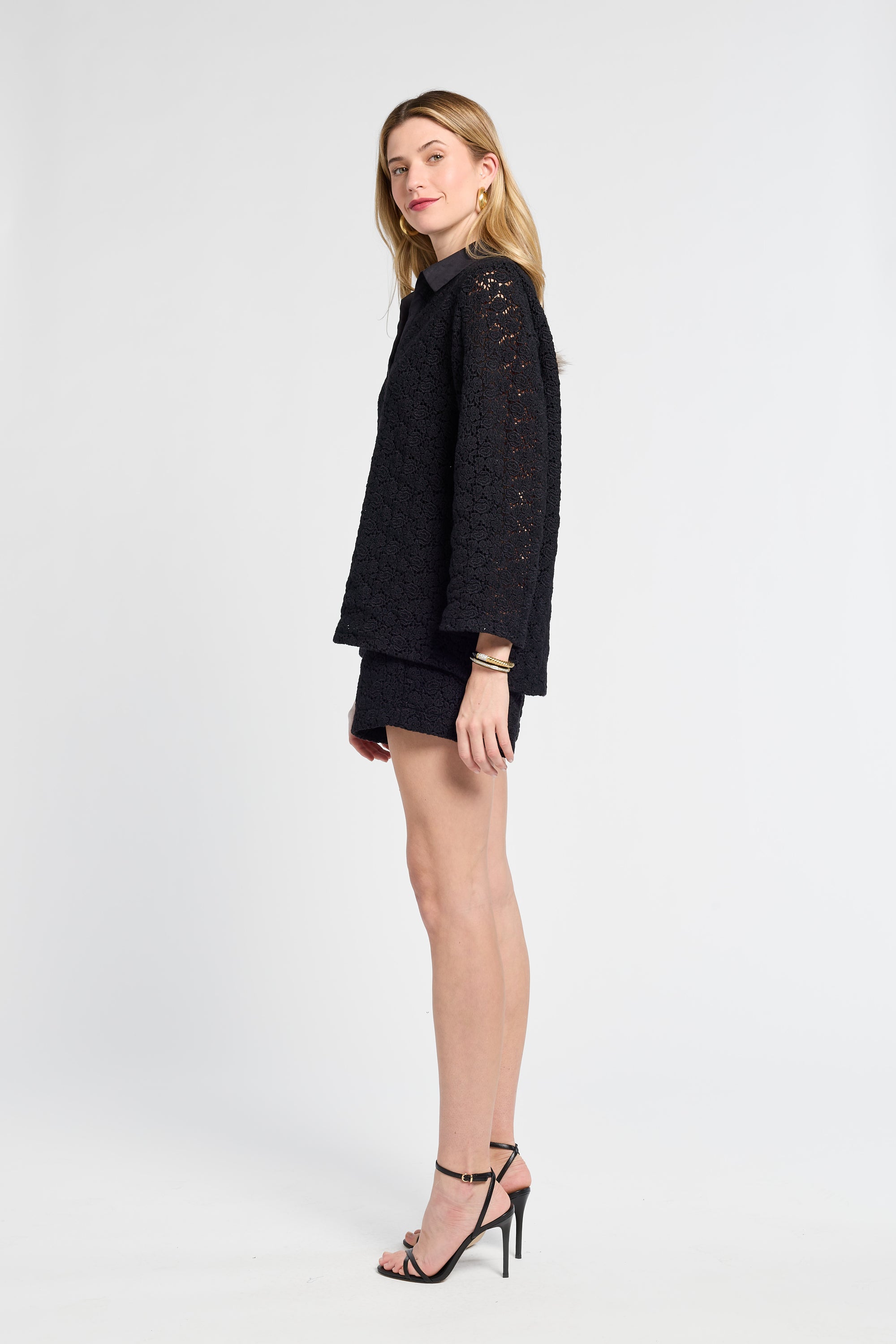 Woman wearing a black lace blouse and shorts on a white background