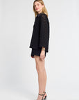 Woman wearing a black lace blouse and shorts on a white background
