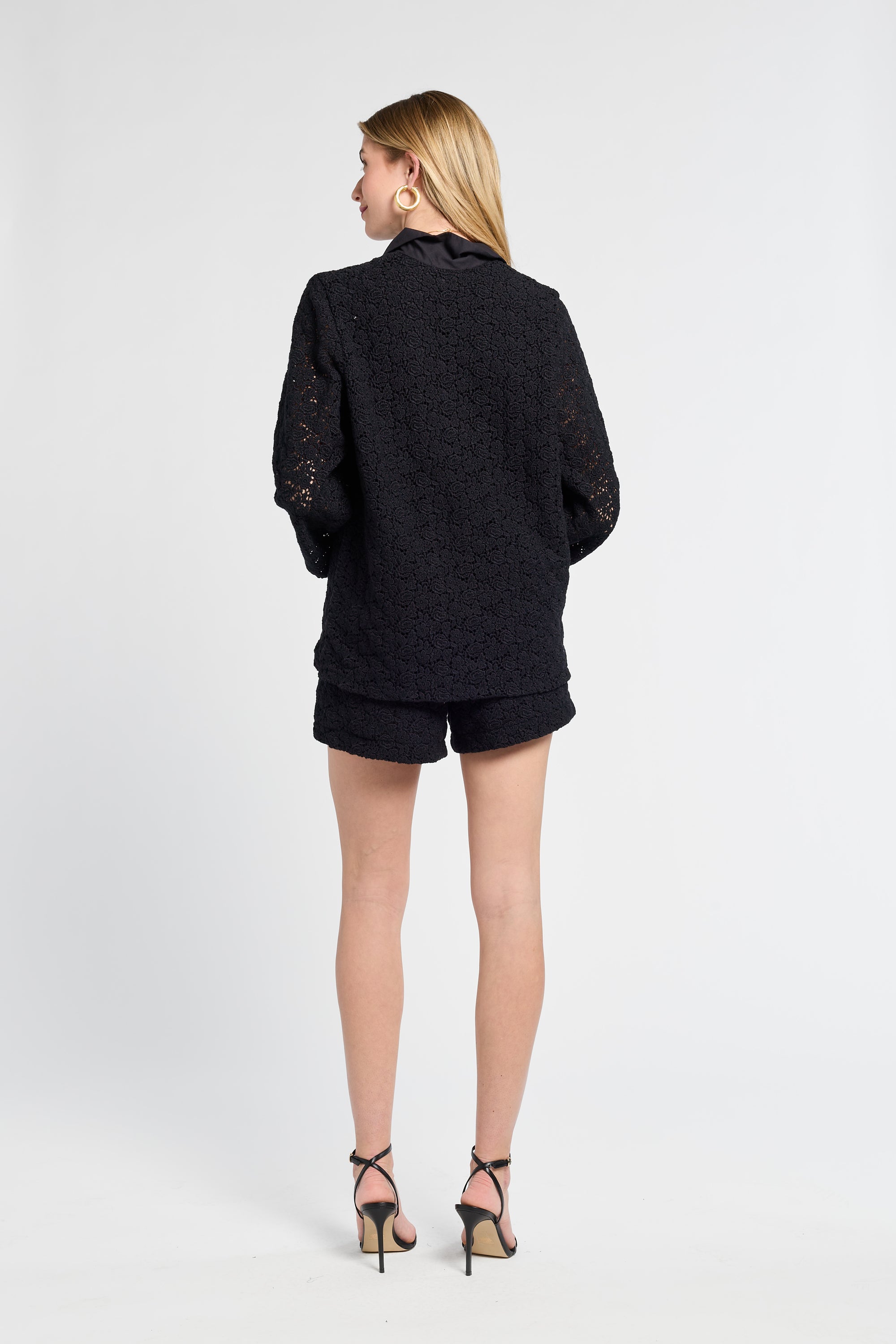 Person wearing a black blouse and shorts on a white backdrop