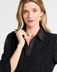 Woman wearing a black v-neck lace blouse against a white backdrop