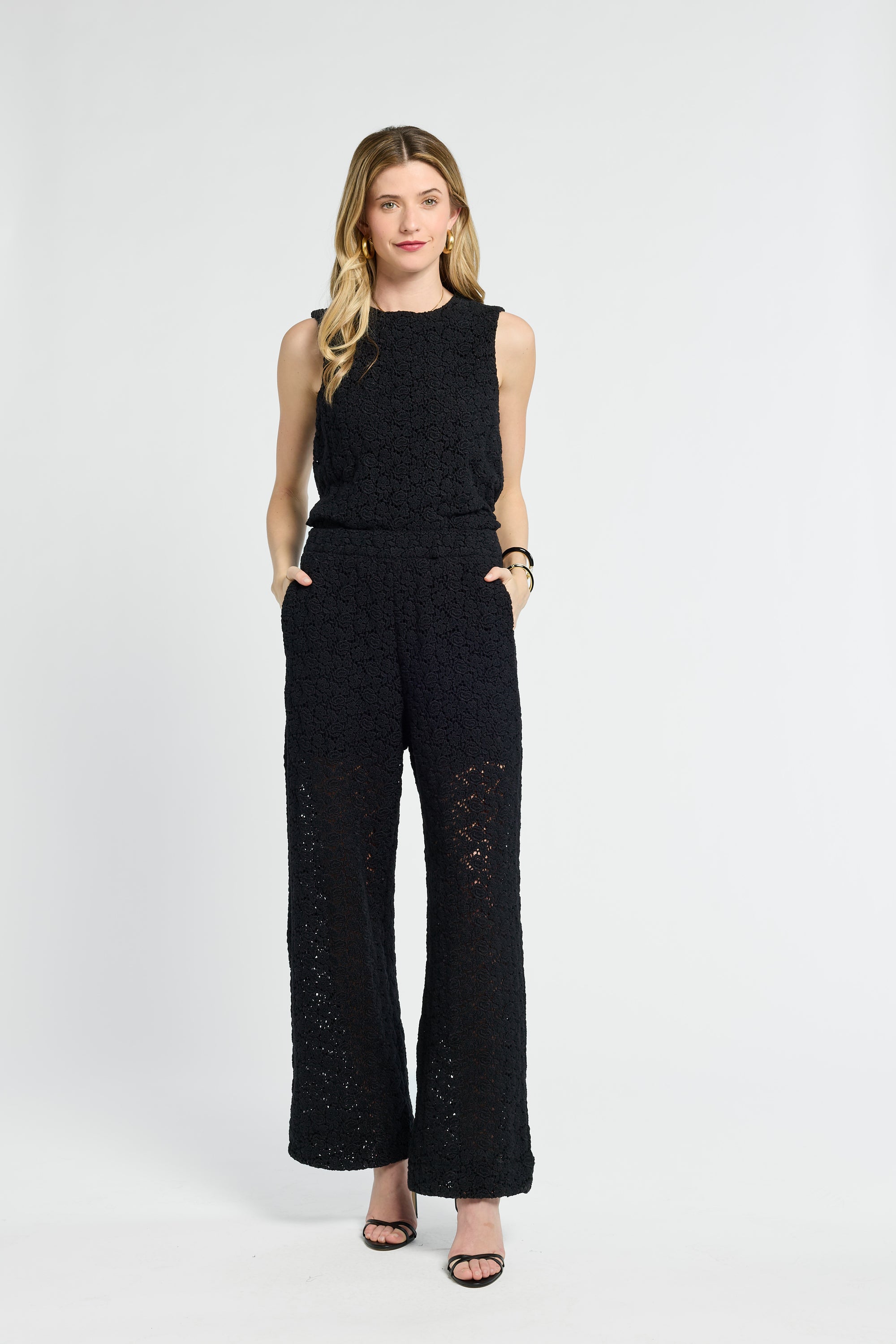 Woman wearing a black sleeveless top and wide-leg pants on a white background