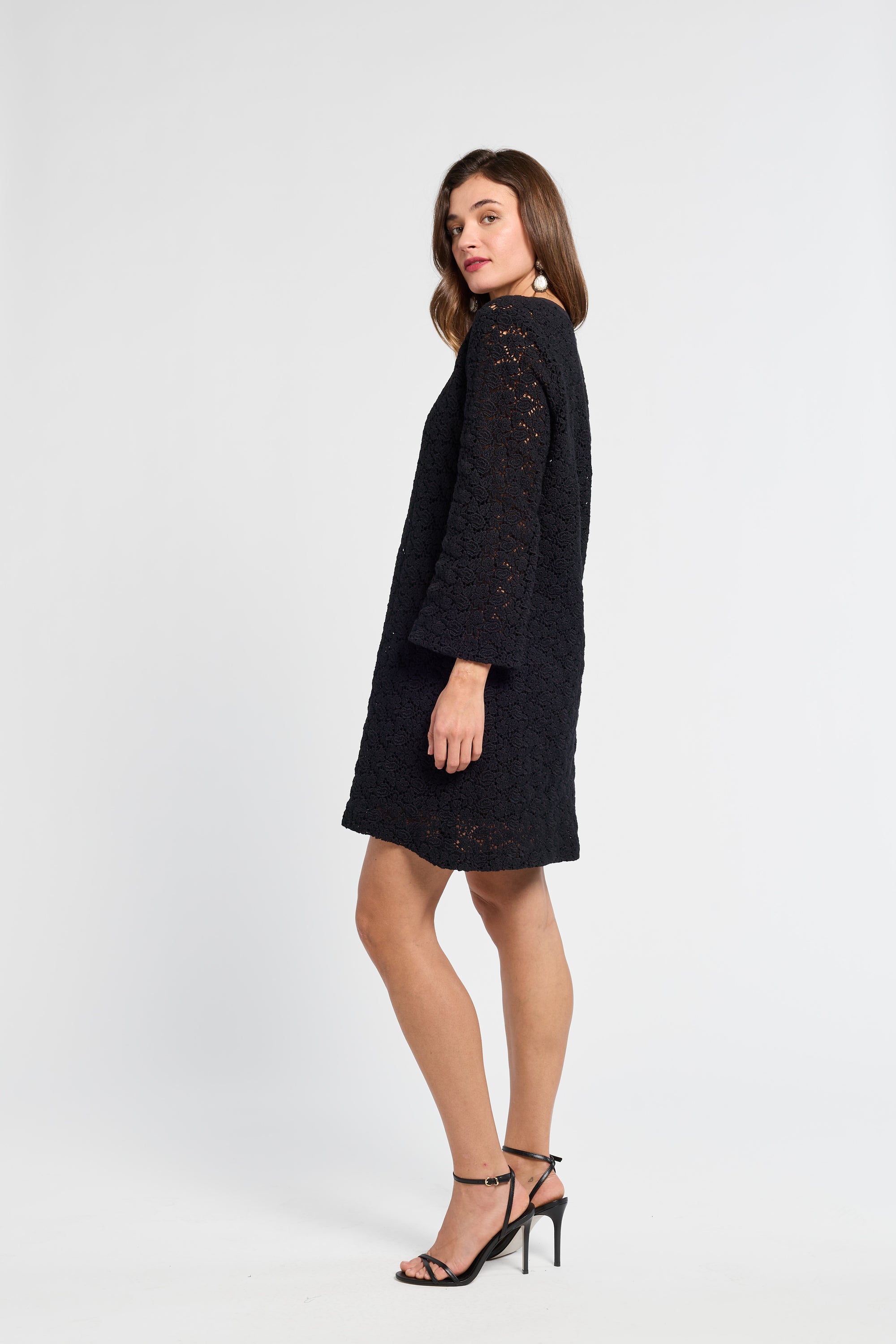 Woman wearing a black dress and black heels on a white background
