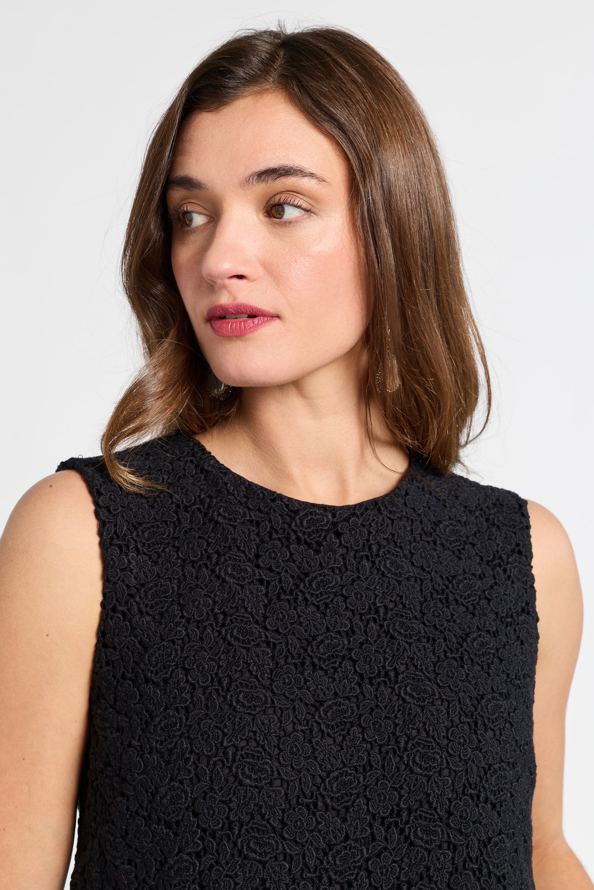 Woman wearing a black sleeveless dress against a white background