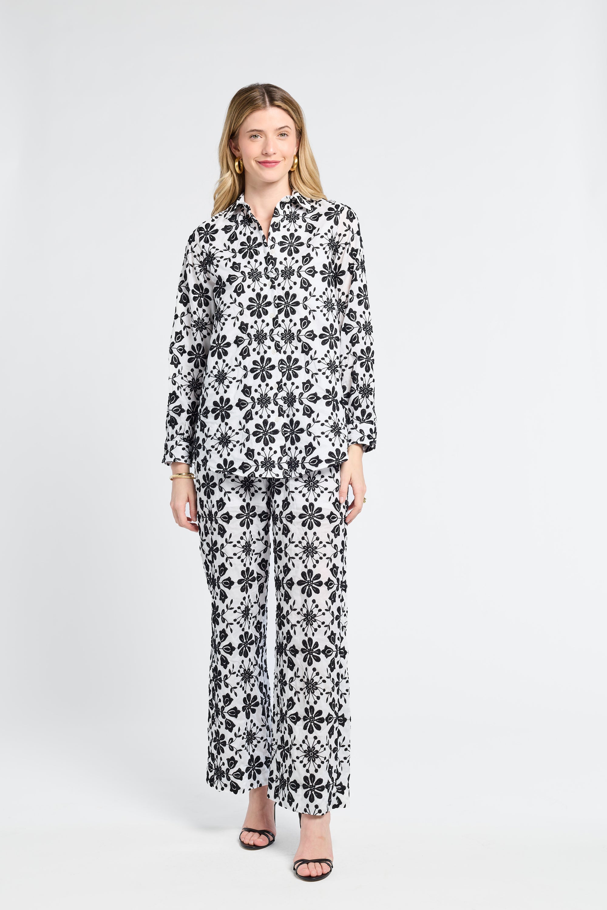 Woman wearing a black and white floral blouse and pants on a white background